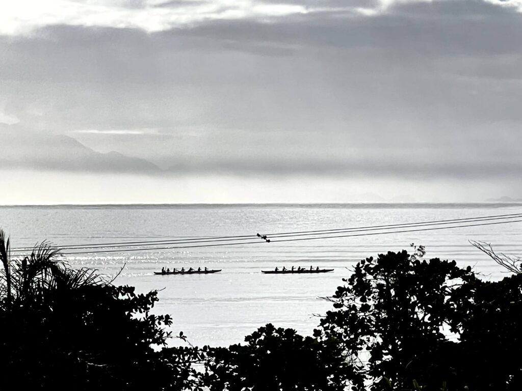 Silhueta de duas canoas havaianas remando ao entardecer no mar de Ubatuba