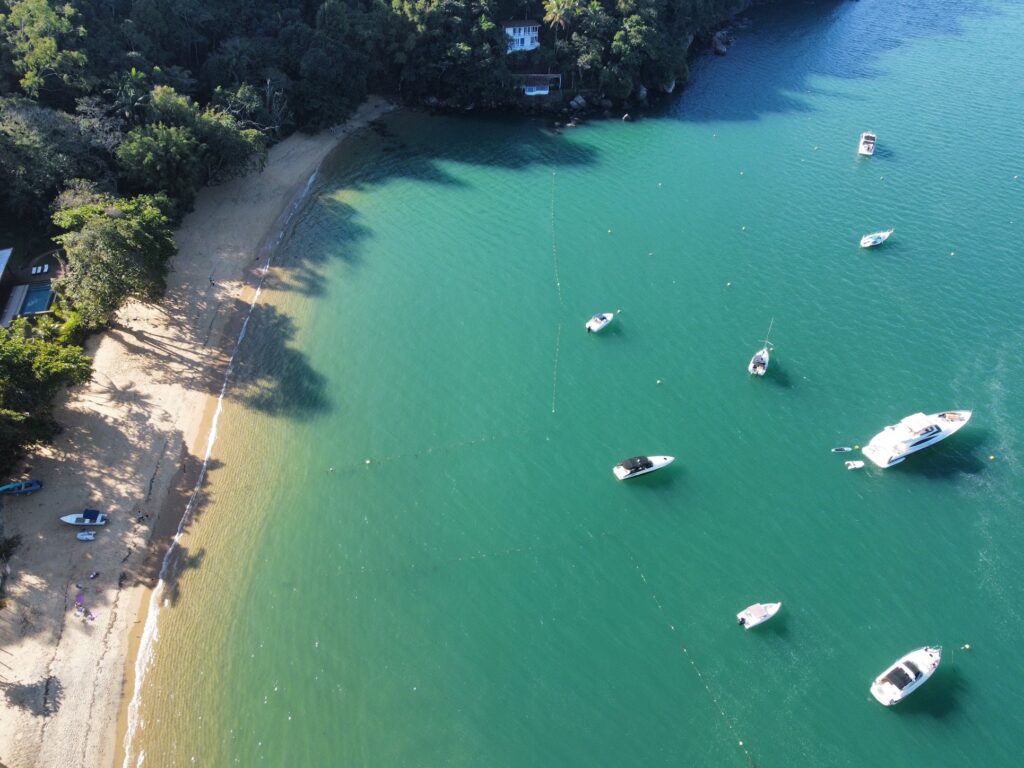 Vista aérea de enseada em Ubatuba com barcos ancorados e faixa de areia