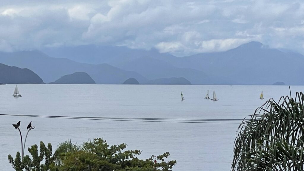 Pescaria cenográfica e pessoas caminhando na orla do Itaguá, Ubatuba
