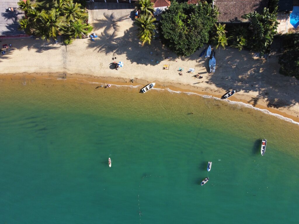 Vista aérea da Praia do Flamengo com areia, mar calmo e barcos na beira