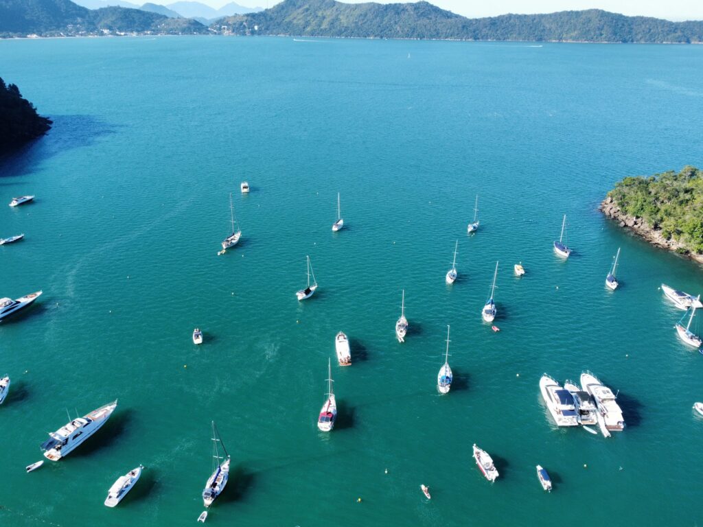 Panorâmica aérea do Saco da Ribeira com veleiros e mar verde-azulado